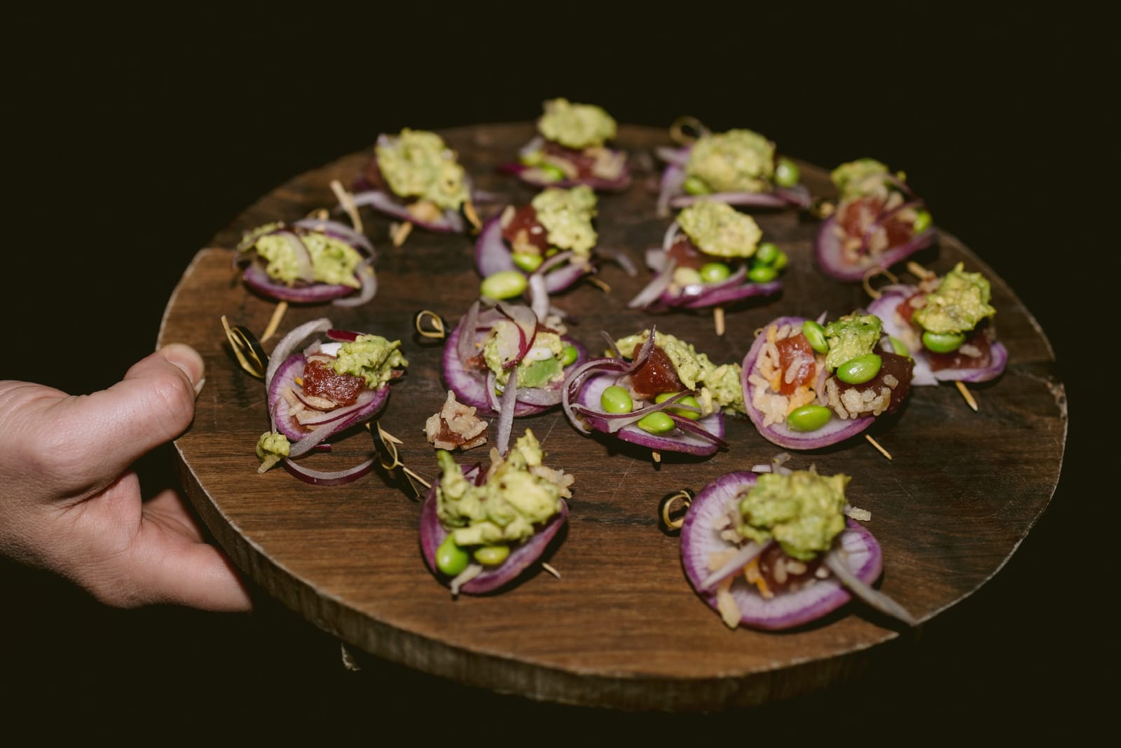 A passed tray of ahi tuna canapés on red onion with edamame and avocado