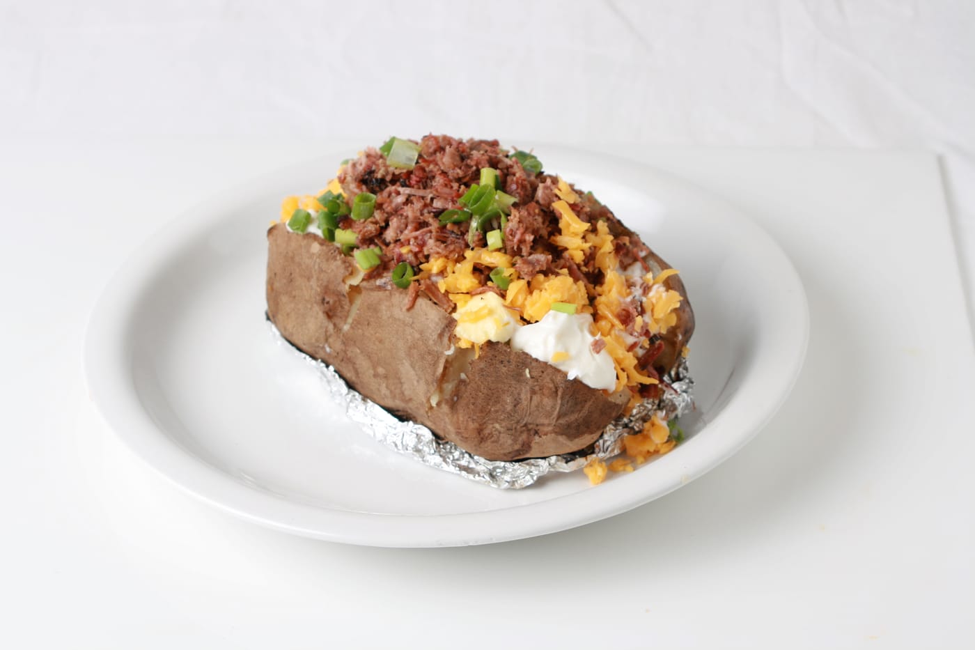 Loaded baked potato topped with chopped brisket, cheddar, sour cream and green onion